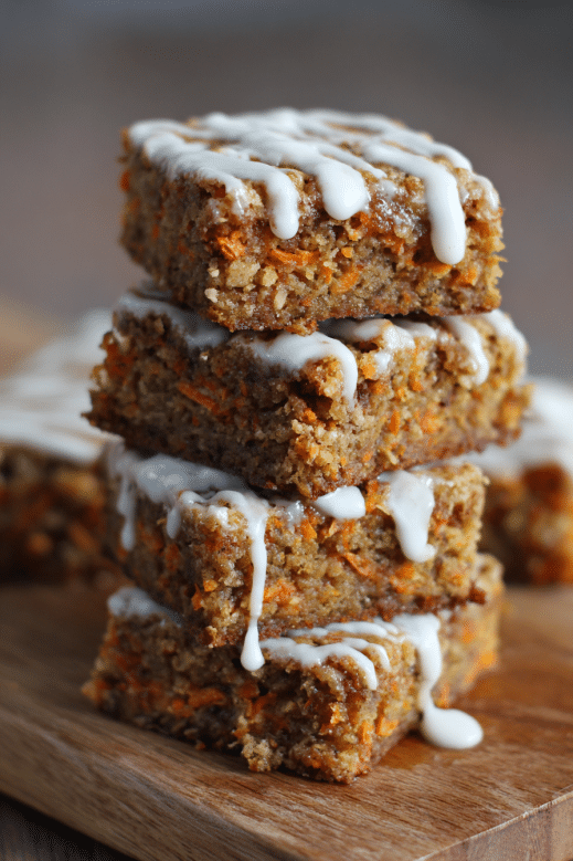 Carrot Cake Bars Everyone Will Love (with Frosting or Without) 6 Carrot cake bars stacked with cream cheese drizzle on wooden board